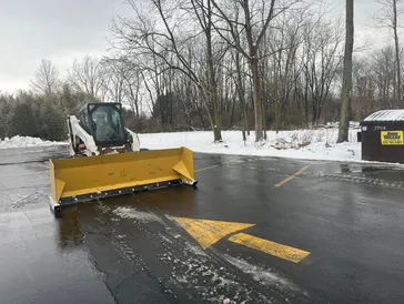 Snow plowing service clearing a commercial parking lot during winter for safe access