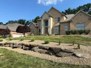 Front yard landscaping with rock bed, large stones, and sloped garden design