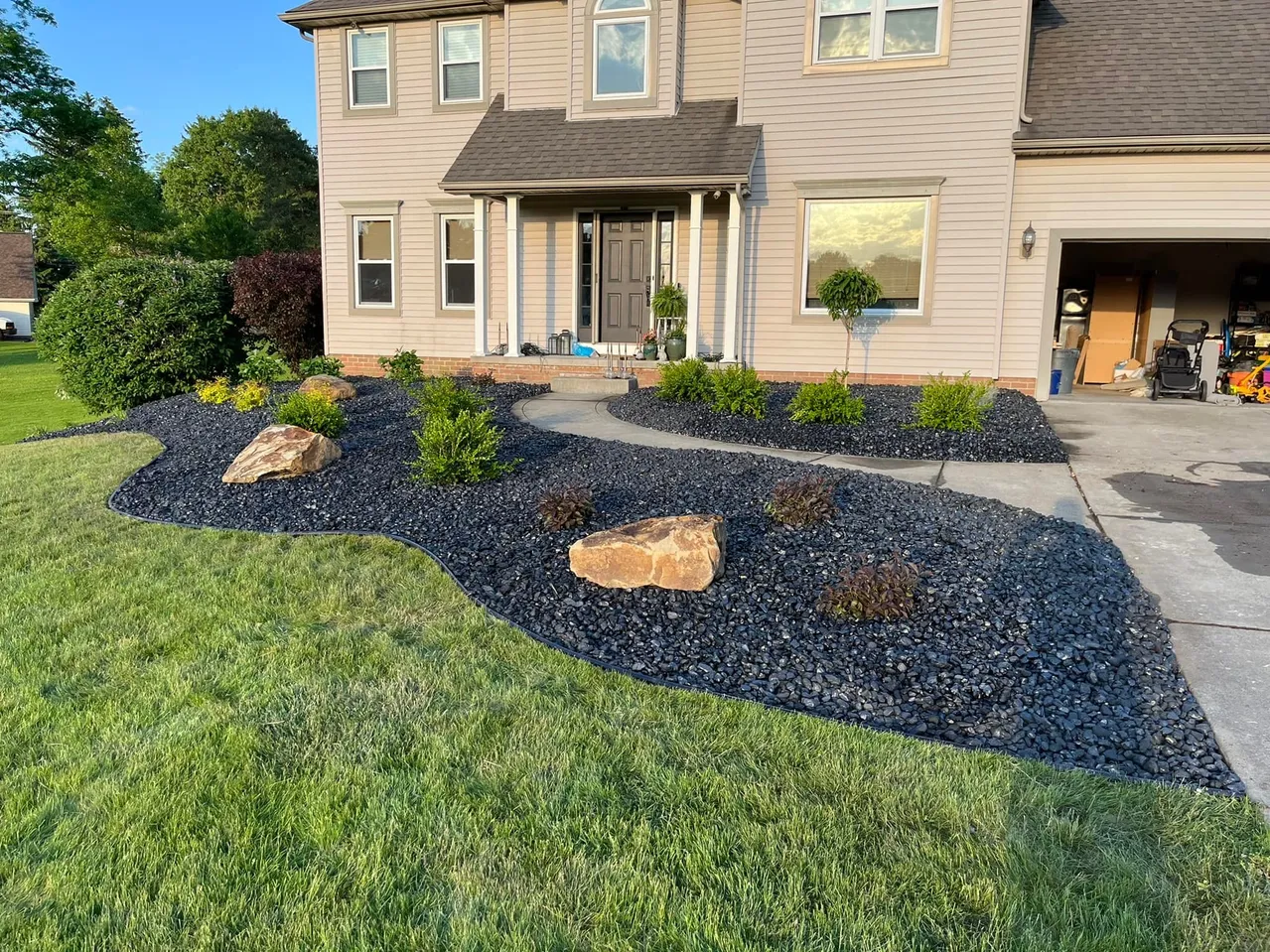 Front yard landscaping with flowering tree, fresh mulch beds, and curved walkway