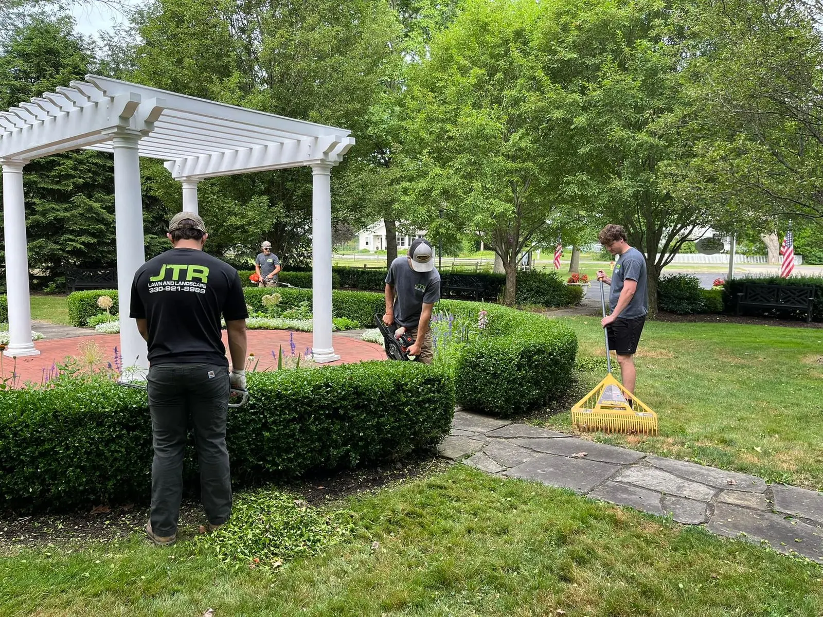 Landscaping team performing hedge trimming and property maintenance