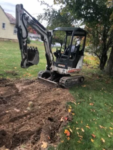 Compact excavator digging trench in residential yard for excavation project