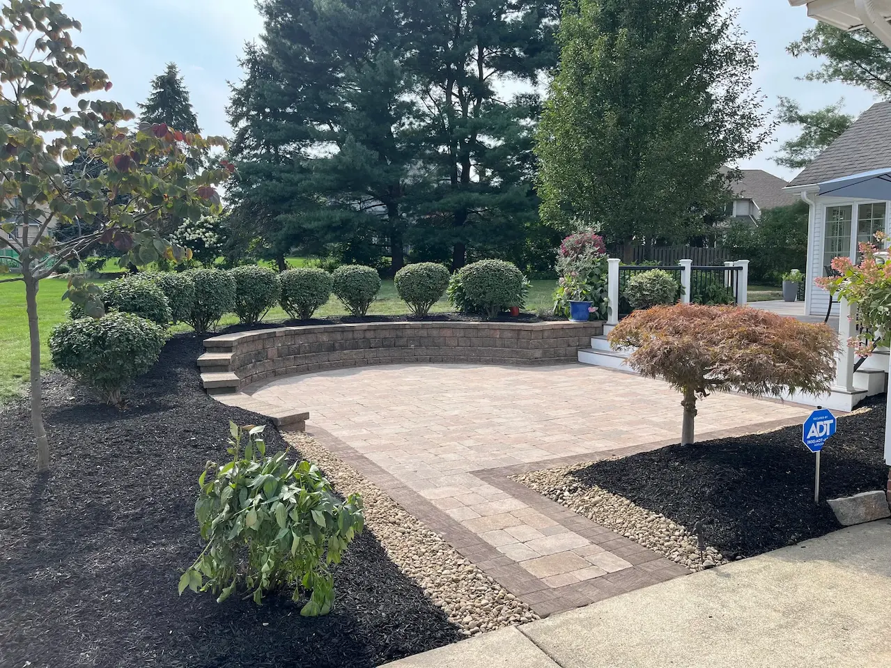 Paver patio and retaining wall hardscaping with landscaped beds at a residential property in Canfield, Ohio