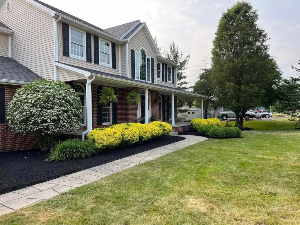 Residential landscaping with trimmed shrubs, mulch beds, and maintained lawn