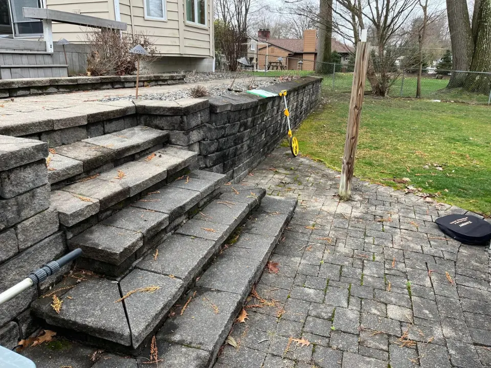 Old retaining wall and steps with worn pavers before replacement